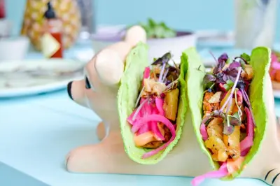 a woman is holding up two tacos at Holiday Inn Express Dubai Safa Park by IHG in Dubai