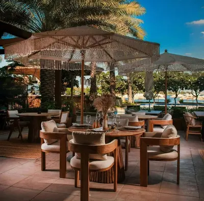 a restaurant with tables and chairs and an umbrella at Luxury - Beachfront - Spacious Shoreline residences - 5 star private beach resort in Dubai