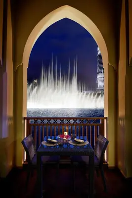 a table with a candle in front of a fountain at Palace Downtown in Dubai