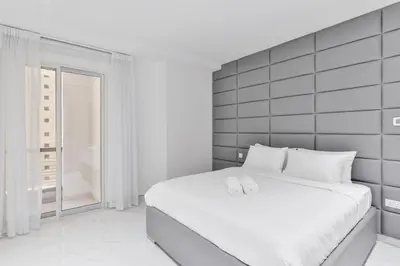 a bedroom with a white bed with two white slippers at Waterfront Luxury 3BR with maids room in JBR, Dubai in Dubai