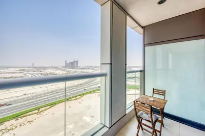 a chair on a balcony with a view of the beach at Maison Privee - Cool Dubai Apt next Burj Khalifa & Design District in Dubai