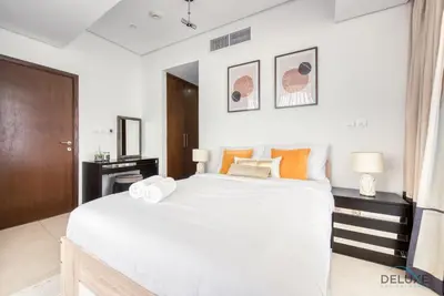 a bedroom with a large white bed with orange pillows at Homely 1BR at The Matrix Dubai Sports City by Deluxe Holiday Homes in Dubai