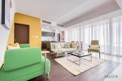 a living room with a green couch and chairs at Homely 1BR at The Matrix Dubai Sports City by Deluxe Holiday Homes in Dubai