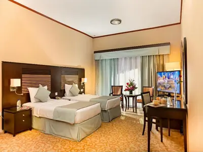 a hotel room with two beds and a desk at Chelsea Gardens Hotel Apartment in Dubai