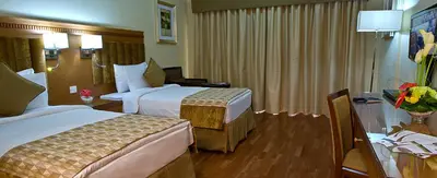 a hotel room with two beds and a table at Chelsea Gardens Hotel Apartment in Dubai