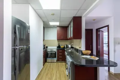 a kitchen with a stainless steel refrigerator and wooden floors at The Smart Concierge - Bahar 6 in Dubai