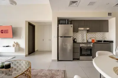 a kitchen with stainless steel appliances and a table at GuestReady Holiday Homes - A Rose in the Sky in Dubai