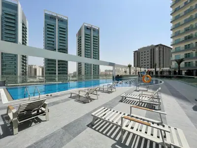 a swimming pool with benches on a building with tall buildings at GuestReady Holiday Homes - A Rose in the Sky in Dubai