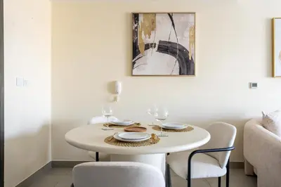 a white dining room table with two chairs and a table at GuestReady Holiday Homes - A Rose in the Sky in Dubai