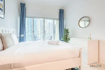 a white bedroom with a large bed and a window at Calm Studio at Lake View Tower JLT by Deluxe Holiday Homes in Dubai