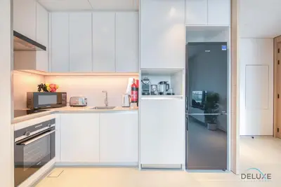 a kitchen with white cabinets and a refrigerator at Classy 1BR at The Address Residences in JBR by Deluxe Holiday Homes in Dubai