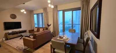 a living room with a table and a couch and a television at Cozy 2 BR apt Golf Tower Greens, stunning Golf views in Dubai