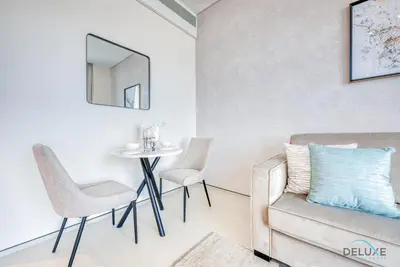 a living room with a couch and a table and chairs at Modern 1BR Oasis in Prime Location, Book Now by Deluxe Holiday Homes in Dubai