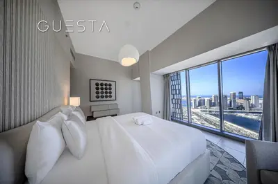 a bedroom with a white bed and a large window at Cayan Tower, Dubai Marina in Dubai
