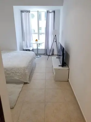 a bedroom with a bed and a television on a tiled floor at Luxury Kings Palace Private Room with Shared Kitchen Next To Barasti Beach in Dubai