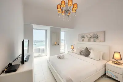 a white bedroom with a bed and a chandelier at Sea Views 1BR in the Heart of Dubai Marina by Deluxe Holiday Homes in Dubai