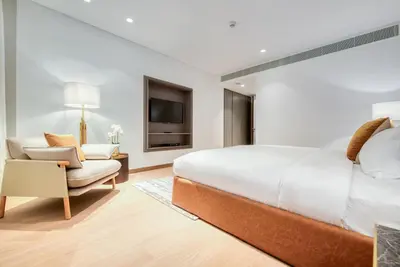 a bedroom with a bed and a chair and a television at Palm Jumeirah Luxury Apartments by Propr in Dubai