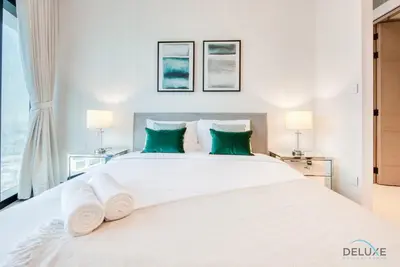 a bedroom with a large white bed with green pillows at Captivating 1BR at The Address Residences in JBR by Deluxe Holiday Homes in Dubai