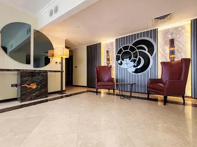 a lobby with two chairs and a wall with a logo at Elan Murjan Rimal Suites, Sea in 3 min walk! 6 Bedrooms & Hall, Massive Layout in Dubai