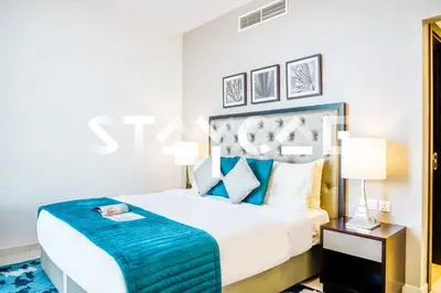 a bedroom with a large white bed with blue accents at Staycae Holiday Homes - Celestia in Dubai