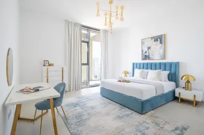 a white and blue bedroom with a bed and a desk at Frank Porter - The Pulse Residences in Dubai