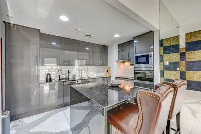 a kitchen with a glass counter and two chairs at VIP Castles JBR Rimal 3 Suite 1 Bedroom in Dubai