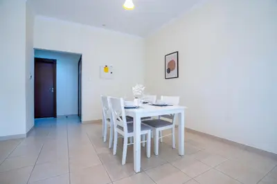 a white dining room with a white table and chairs at RH- Prime Location, Spacious 2BR, walk to Dubai Mall in Dubai