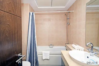 a bathroom with a tub and a sink and a toilet at Steps Away From the Beach & Entertainment Hubs 1BR Unit, Torch Tower, Dubai Marina by Deluxe Holiday Homes in Dubai