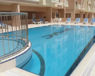 a large swimming pool with blue chairs in a hotel at Huge Entire apartment for Couples ,families & Groups -up to 5 Guests- with free pool, steam & Sauna ,JVC,Dubai in Dubai