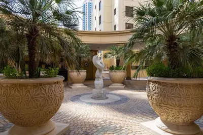 a courtyard with palm trees and a statue in a building at Frank Porter - Murjan 6 in Dubai