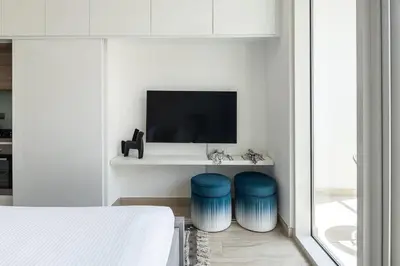 a bedroom with two blue stools in front of a tv at Frank Porter - Studio One in Dubai