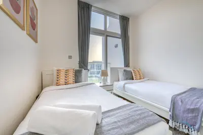 two beds in a room with a window at Delightful 3BR Townhouse at DAMAC Hills 2 Dubailand by Deluxe Holiday Homes in Dubai