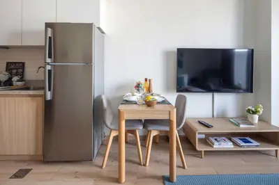 a kitchen with a table and a stainless steel refrigerator at Frank Porter - Aura by Azizi in Dubai