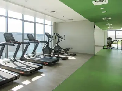 a gym with several tread machines in a room with windows at Frank Porter - Aura by Azizi in Dubai