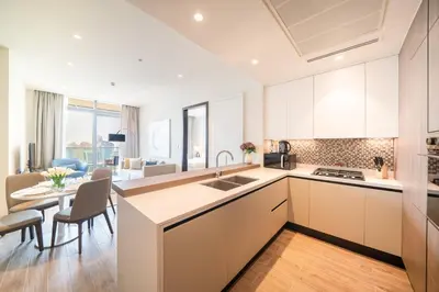 a kitchen with white cabinets and a dining room at Luton Vacation Homes - Marina View & Luxury 1BR - Jumeirah Living Marina Gate Tower 3 - 54AB49AB36AB in Dubai