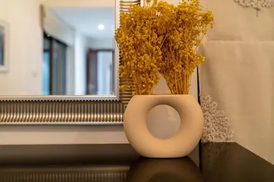 a white vase with yellow flowers sitting on a window sill at Spectacular Burj & Fountain View - Luxurious 3 Bedrooms & Maids room - The Residences in Dubai