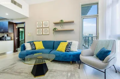 a blue couch and two chairs in a living room at bnbmehomes - La Fontana in Dubai