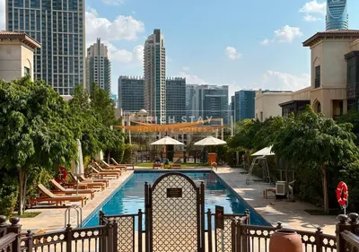 a pool with chairs and umbrellas and a city skyline at Spectacular 2BR in Souk Al Bahar, Downtown with Burj & Dubai Mall view by Rich Stay in Dubai