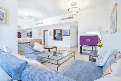 a living room with blue couches and a tv at Gardenia Rimal Suites, Luxury Apartments in JBR with 2 min Walk to JBR beach in Dubai