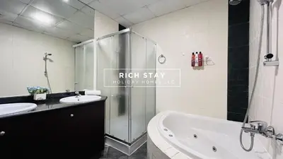 a bathroom with a shower and a tub and a sink at Canal View 2BR & Maid Room in KG Tower, Dubai Marina in Dubai