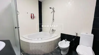 a bathroom with a tub and a toilet and a sink at Canal View 2BR & Maid Room in KG Tower, Dubai Marina in Dubai