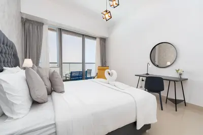 a white bedroom with a large bed and a desk at White Sage - Incredible Full Sea and Dubai Eye View in Marina in Dubai