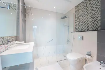 a bathroom with a sink and a toilet and a shower at Downtown Damac Distinction Full Burj View in Dubai