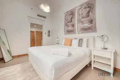 a white bedroom with a large bed and a table at Lively 1 BR at Al Nabat Shoreline 8 Palm Jumeirah by Deluxe Holiday Homes in Dubai