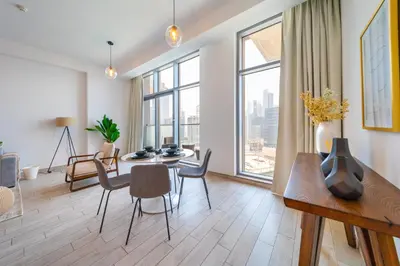 a living room with a table and chairs and a large window at EDEN'S Homes & Villas - Atria Residences in Dubai