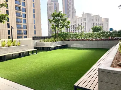 a green lawn in a city with benches and buildings at Ultimate Luxury at Dubai Creek Horizon Waterfront in Dubai