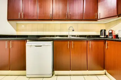 a kitchen with wooden cabinets and a white dishwasher at Wonderful 2 Bedroom apartment in JBR in Dubai