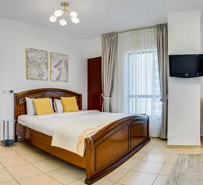 a bedroom with a bed with yellow pillows and a tv at Wonderful 2 Bedroom apartment in JBR in Dubai