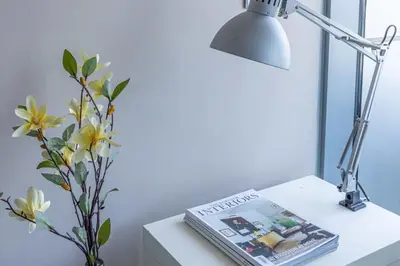 a table with a lamp and a magazine and a vase with flowers at Frank Porter - Indigo Tower in Dubai