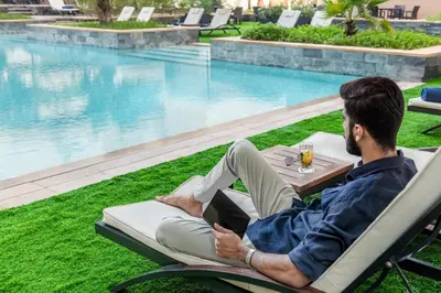 a man sitting in a chair with a laptop next to a pool at The H Dubai in Dubai